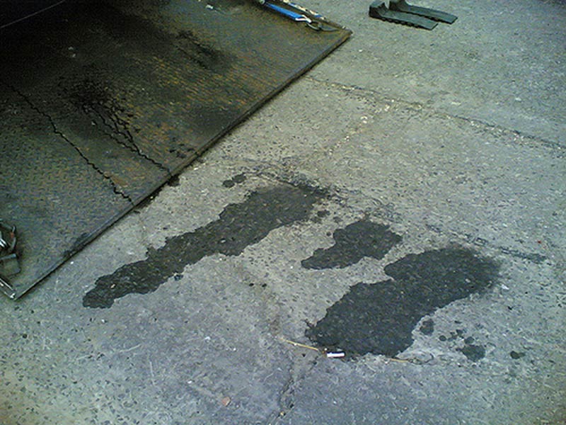 Dark oil-like stains on a concrete floor near a metal ramp.