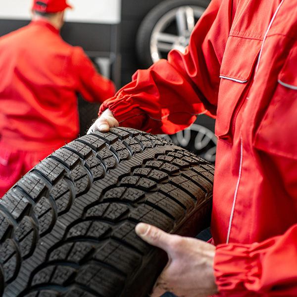 Worker in uniform carrying new tires at the car service
