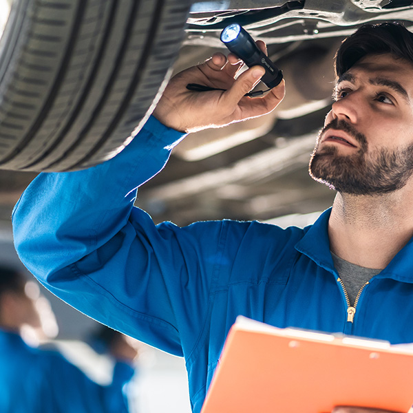 Vehicle service maintenance handsome man checking under car condition in garage