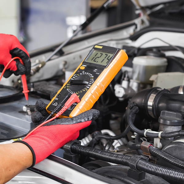 A technician is checking the car battery for availability