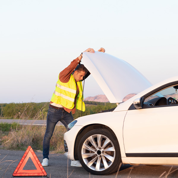 Man on a vest leaning on an open car hood