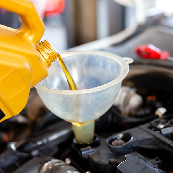 Pouring motor oil for motor vehicles from a gray bottle into the engine