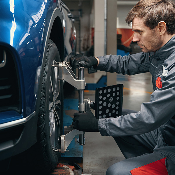 Male inspecting wheel alignment in the workshop