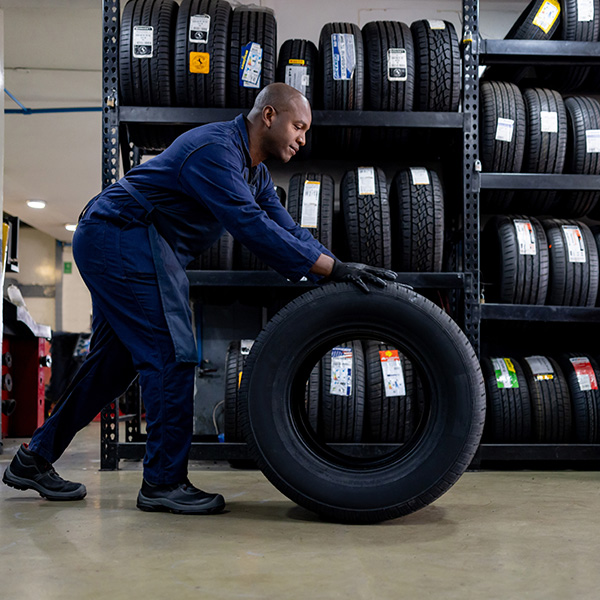Mechanic changing a flat tire and carrying a wheel at a repair garage