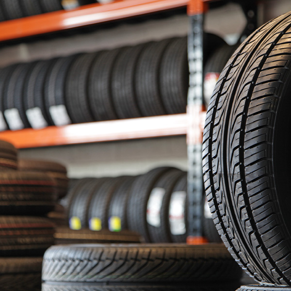Mechanic holding a new car tire looking upward