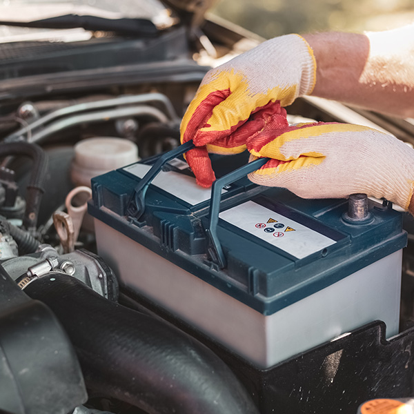 A mechanic removes a car battery from the box