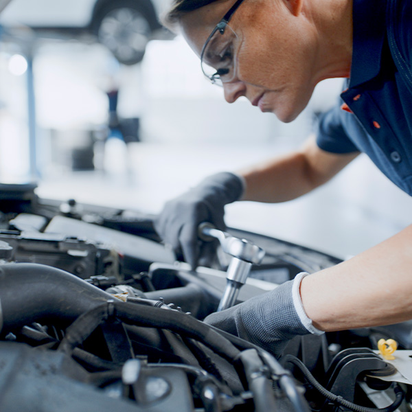 Female mechanic with socket wrench working on car engine