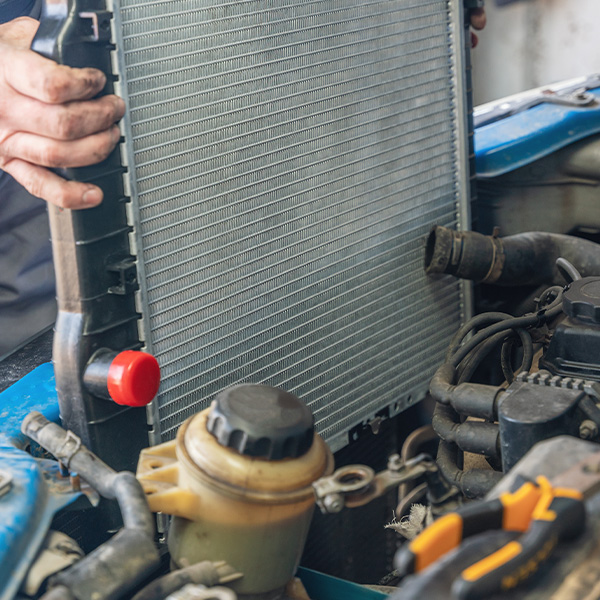 A man installs a new radiator in a car