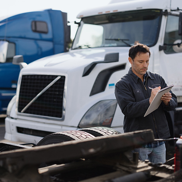 Truck driver inspecting a semi-truck trailer in a parking lot