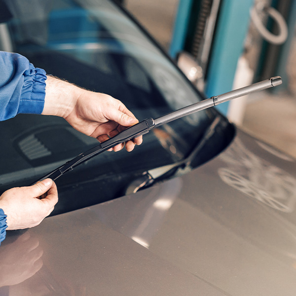 Technician is changing windscreen wipers on a car station