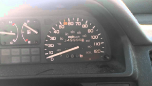 Close-up of a car dashboard showing speedometer and odometer reading 249999 miles.