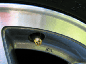 Close-up of a car tire valve on a metal wheel rim.