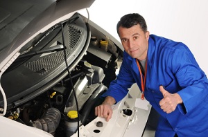 Mechanic inspecting car engine with hood open