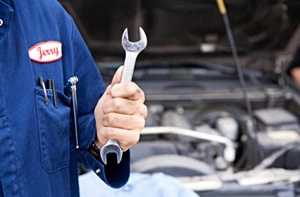 Mechanic holding a wrench near an open car hood
