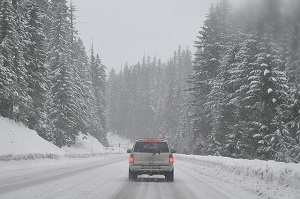Pickup truck driving on a snow-covered road through forest