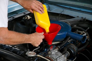 Pouring motor oil into car engine using a funnel