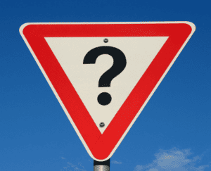Triangular road sign with a question mark on a clear blue sky background.