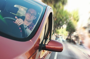 Side view of a red car driving on a city street.