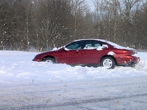 Red car stuck in deep snow on a winter road