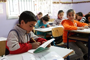 Students sitting at desks and writing in notebooks inside a classroom