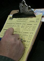 Hand filling out a vehicle inspection checklist on a clipboard